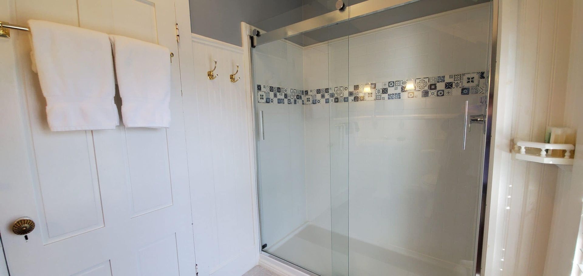 A bathroom with a walk in shower and towels hanging on the wall.