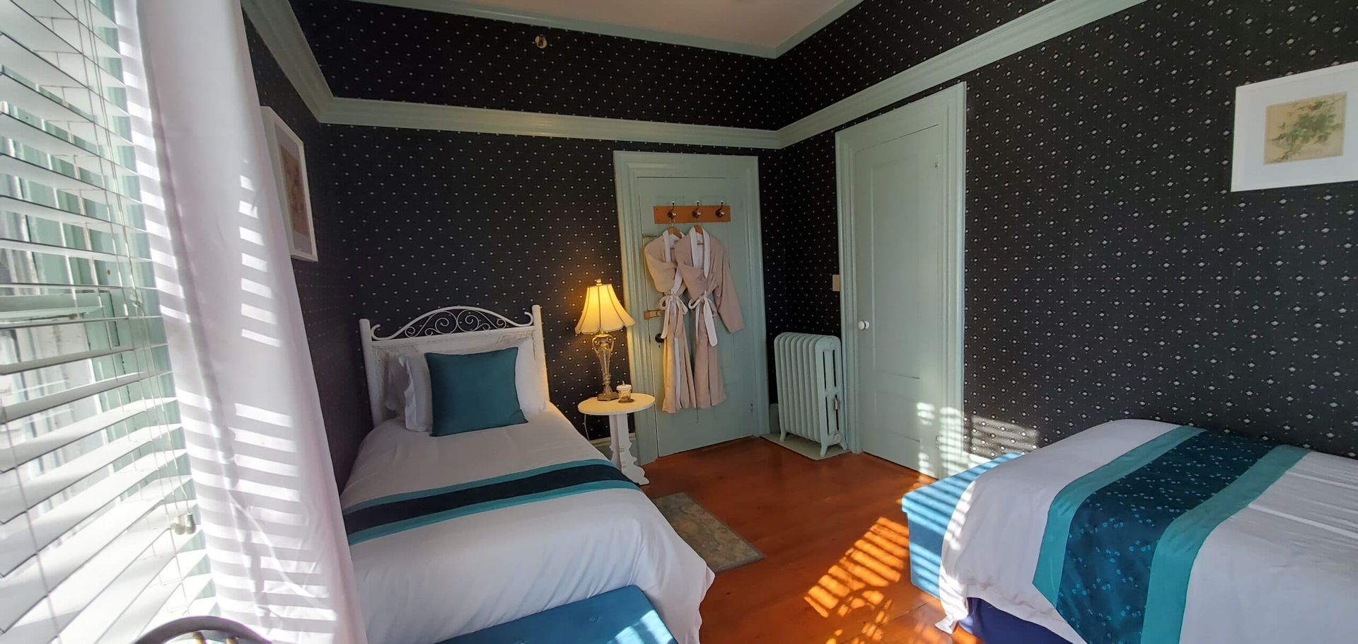 A bedroom with two beds and a window with blinds.