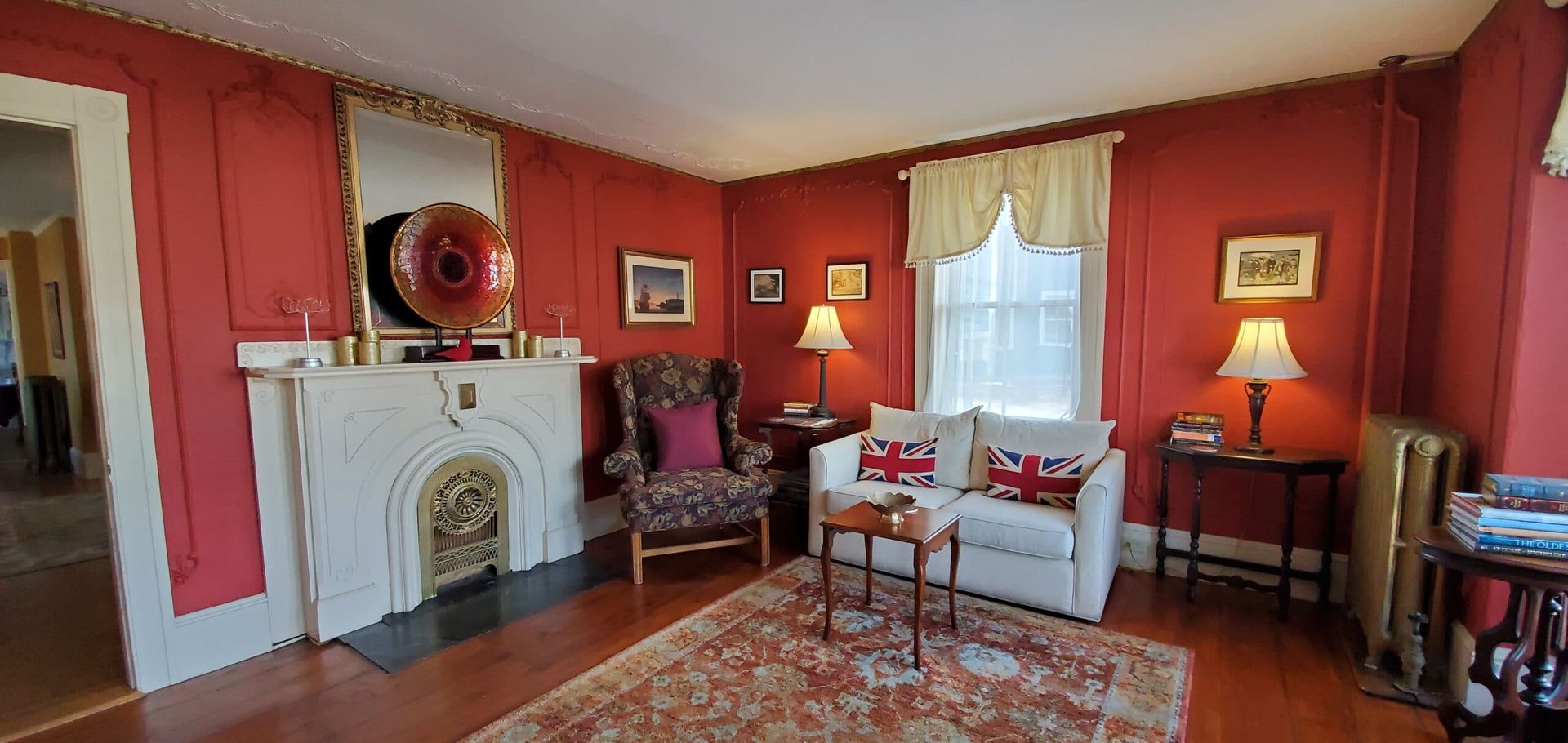 A living room with red walls , a fireplace , a couch and a chair.
