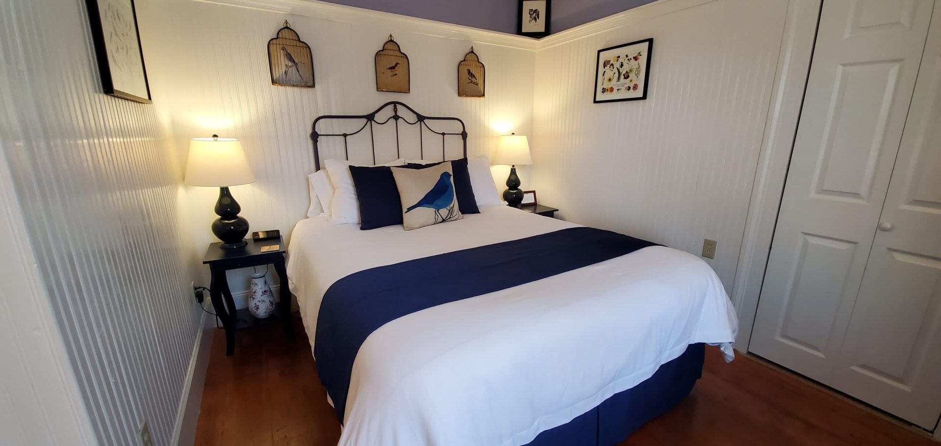 A bedroom with a bed , nightstand , lamps and a purple ceiling.