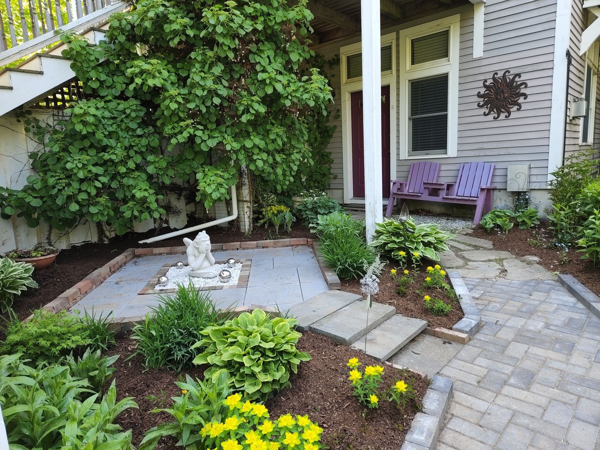 A patio with flowers and a bench in front of a house
