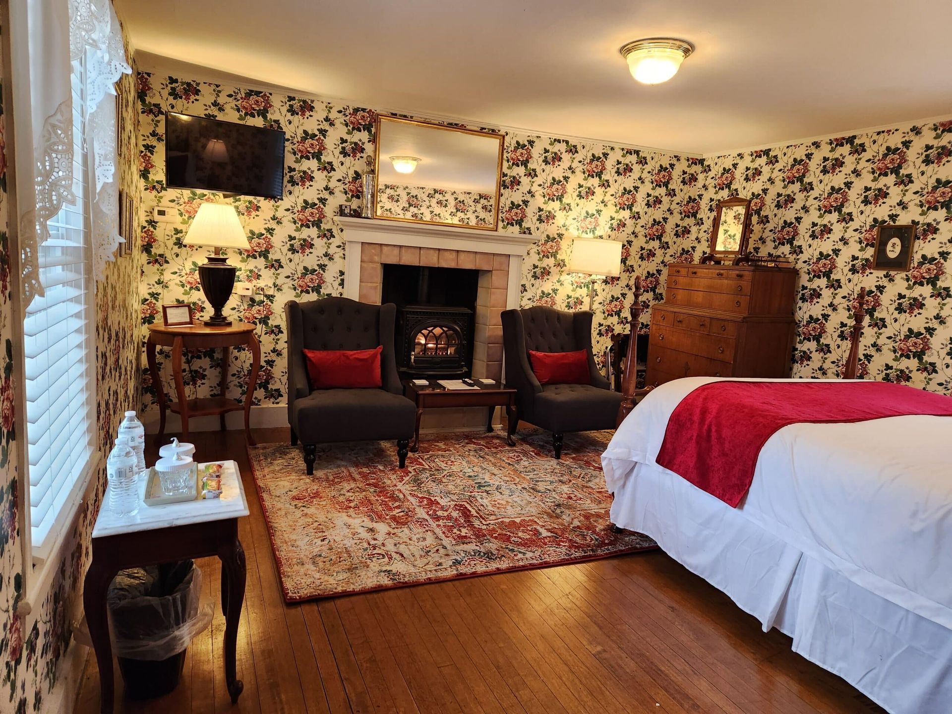 A bedroom with a bed , chairs , and a fireplace.