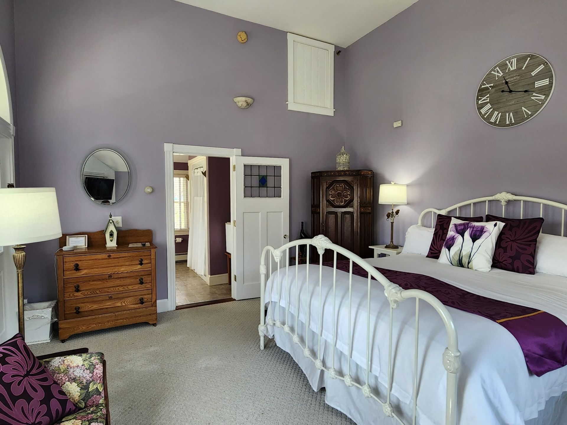 A bedroom with purple walls and a white bed