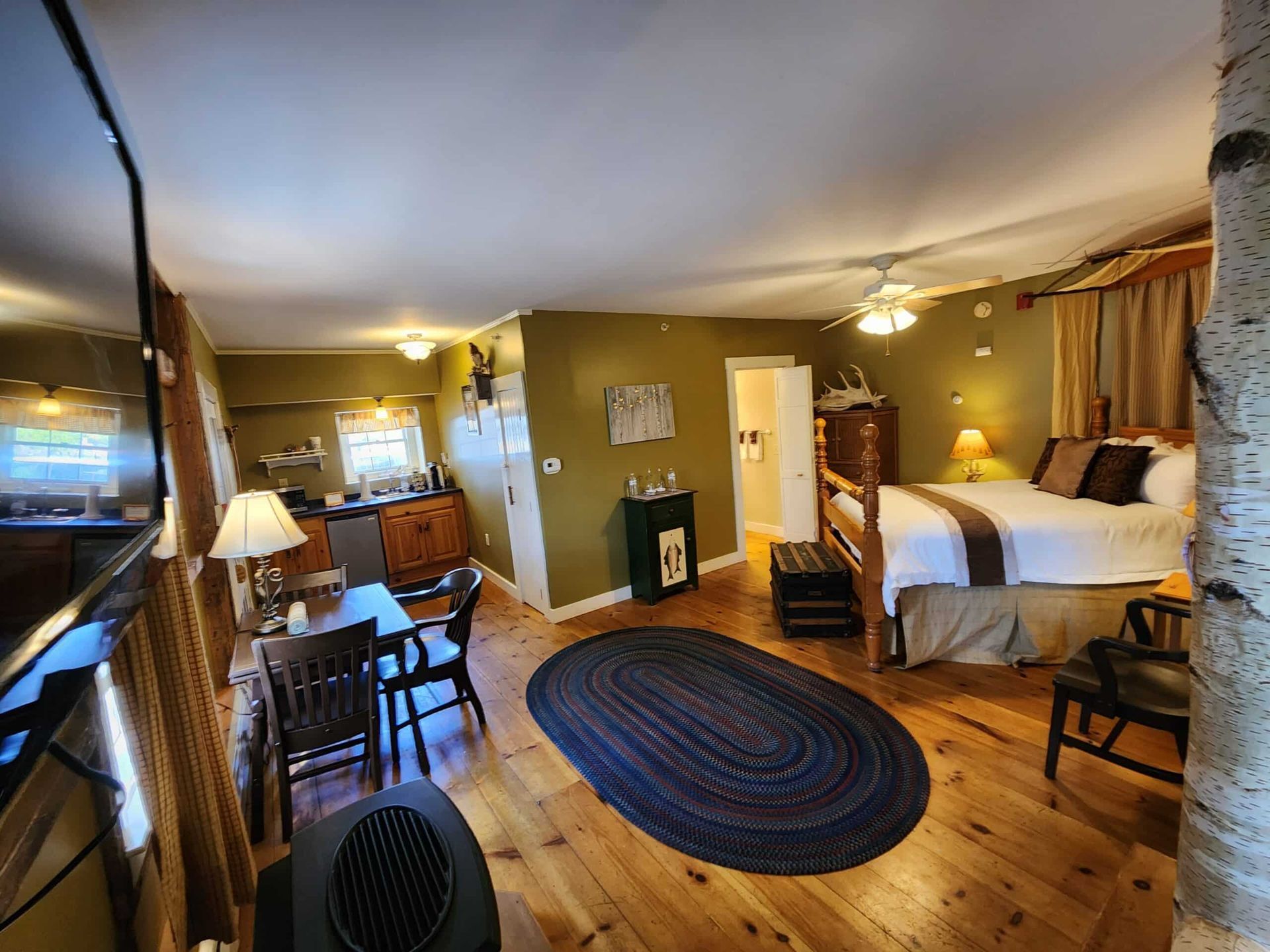 A large room with two beds , a dining table , chairs and a rug.