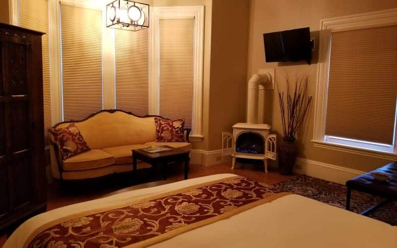 A bedroom with a bed , couch , television and fireplace.