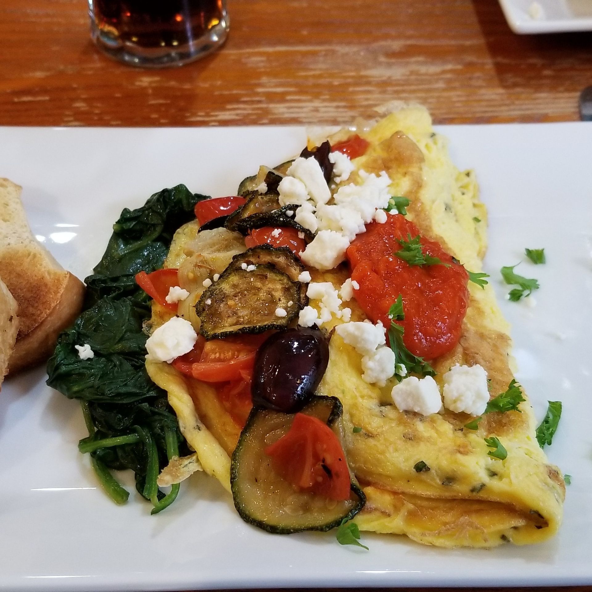 A white plate topped with a vegetable omelet and a piece of bread