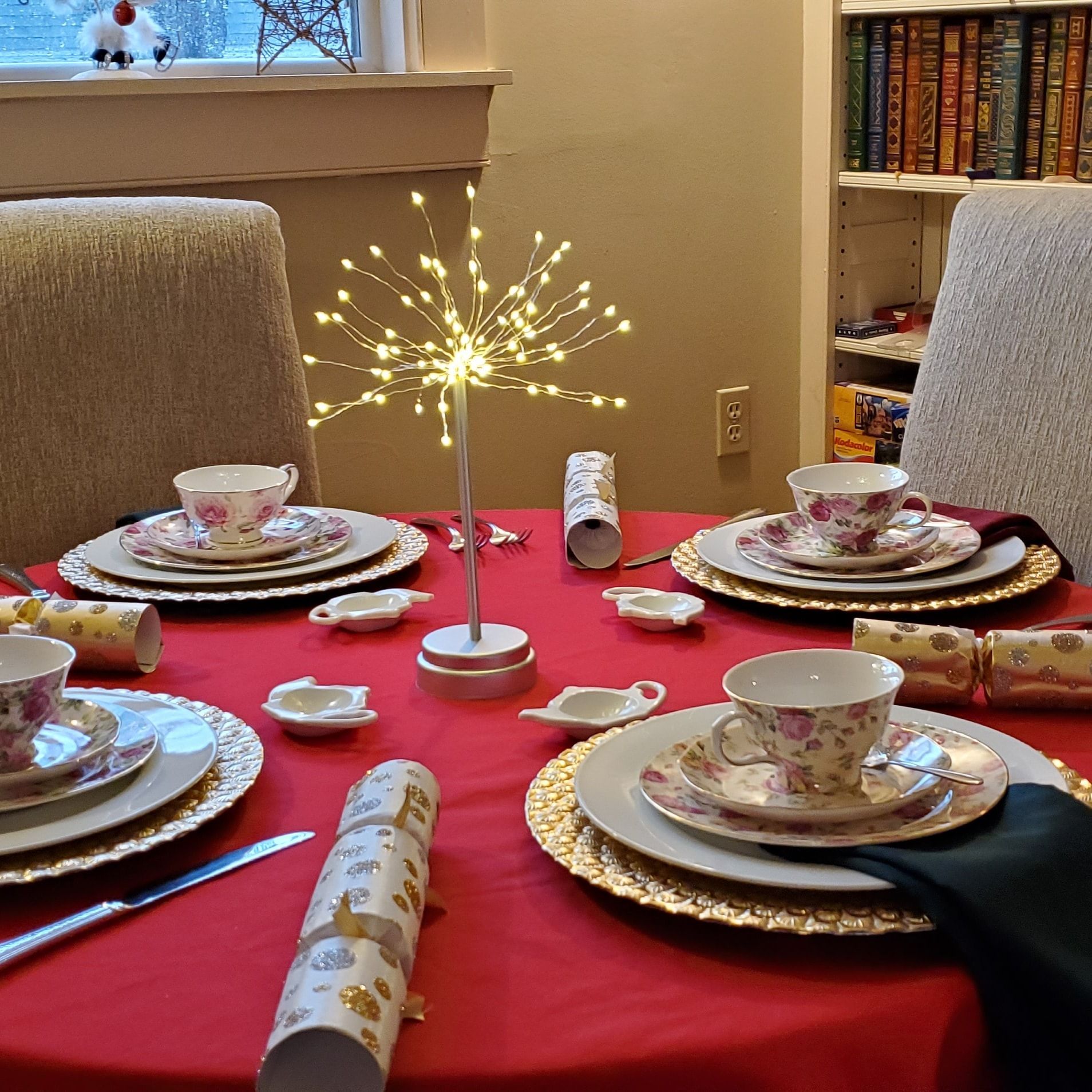 A table set for a christmas dinner with plates cups and crackers