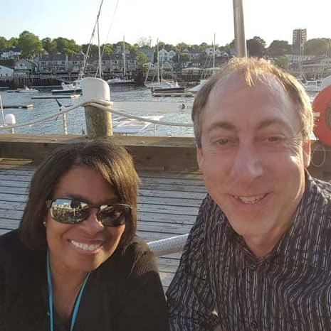 A man and a woman are posing for a picture on a dock.