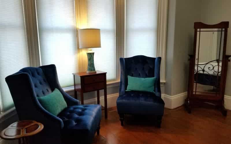 Two blue chairs are sitting in a living room next to a window.