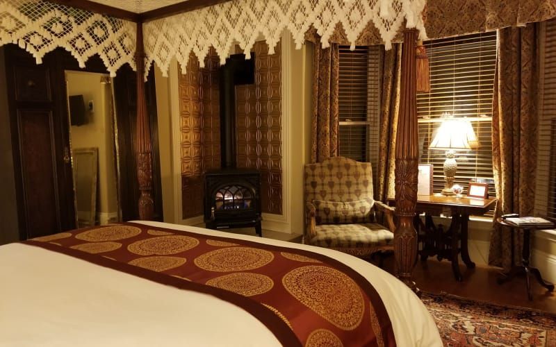 A hotel room with a canopy bed and chairs