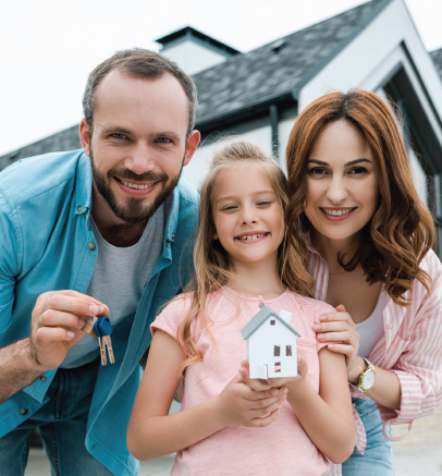 Family smiling in front of a house, holding keys and a miniature house.