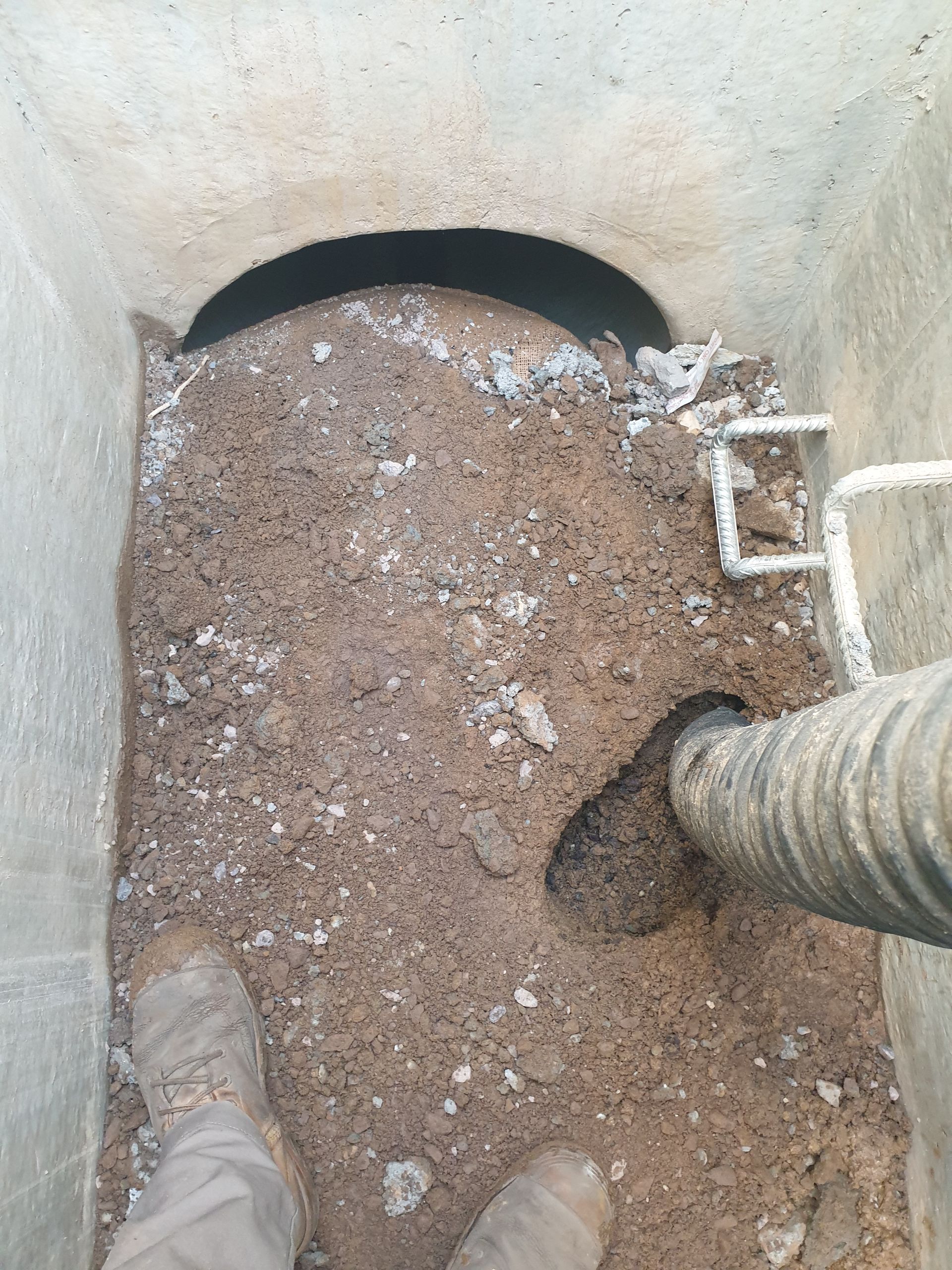 Septic tank interior with accumulated sludge, showing a hose and access opening. Concrete structure — Pro Pipe Solutions in Queanbeyan, NSW