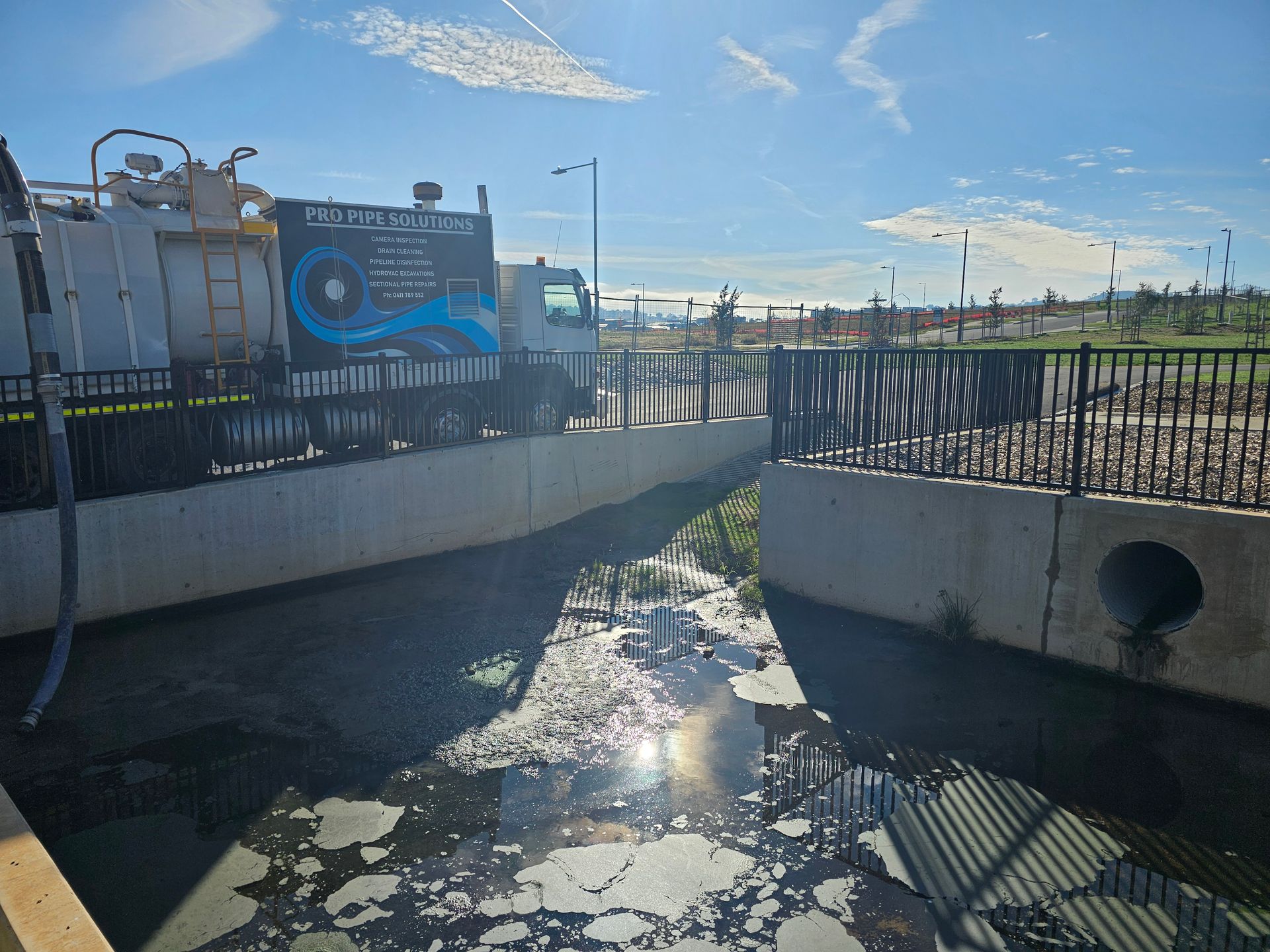 Truck parked near a polluted waterway with a concrete bank and a cloudy sky — Pro Pipe Solutions in Queanbeyan, NSW