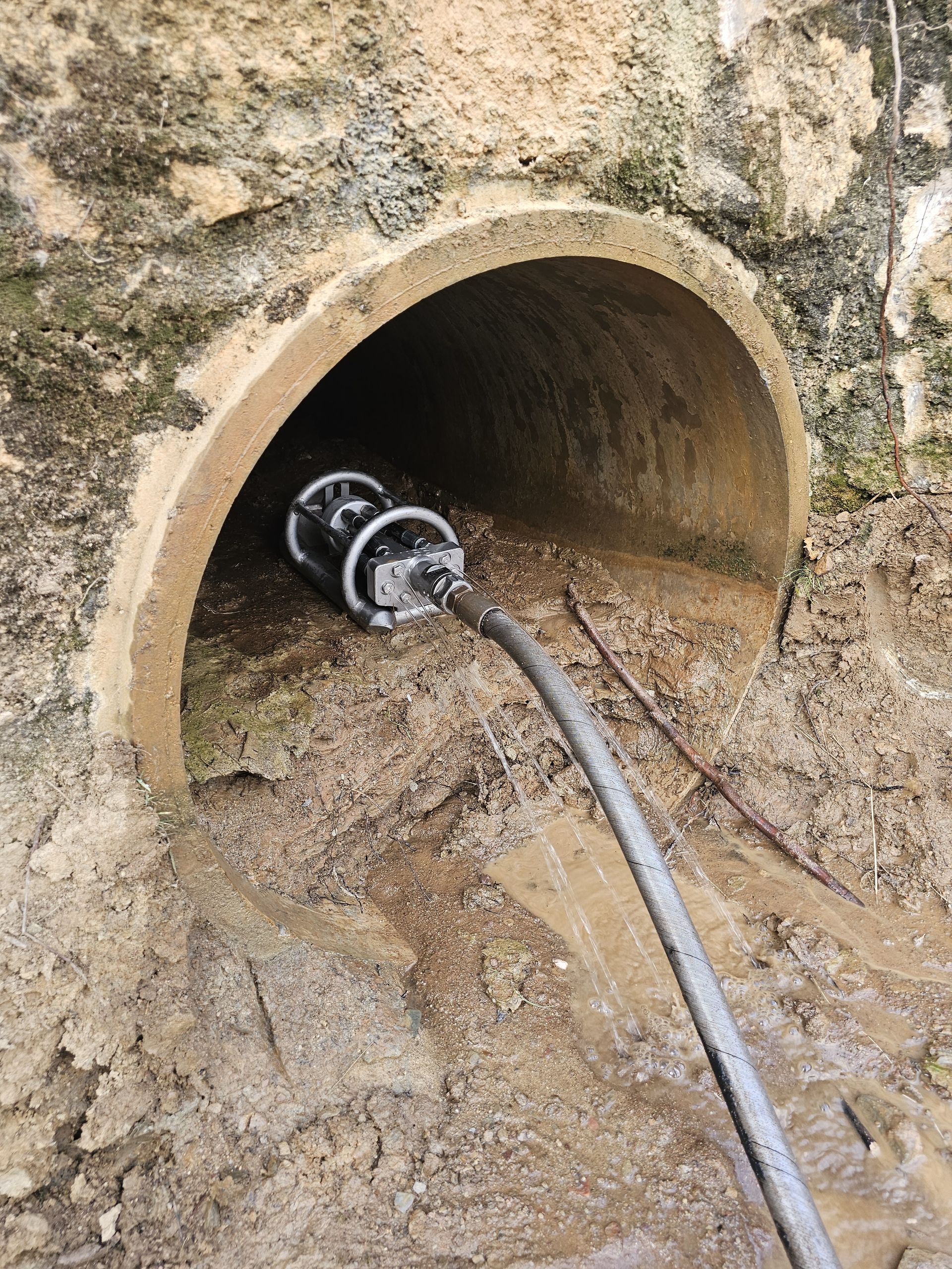 A camera on wheels inside a concrete pipe, inspecting the drain. The setting is outdoors with muddy surroundings — Pro Pipe Solutions in Queanbeyan, NSW