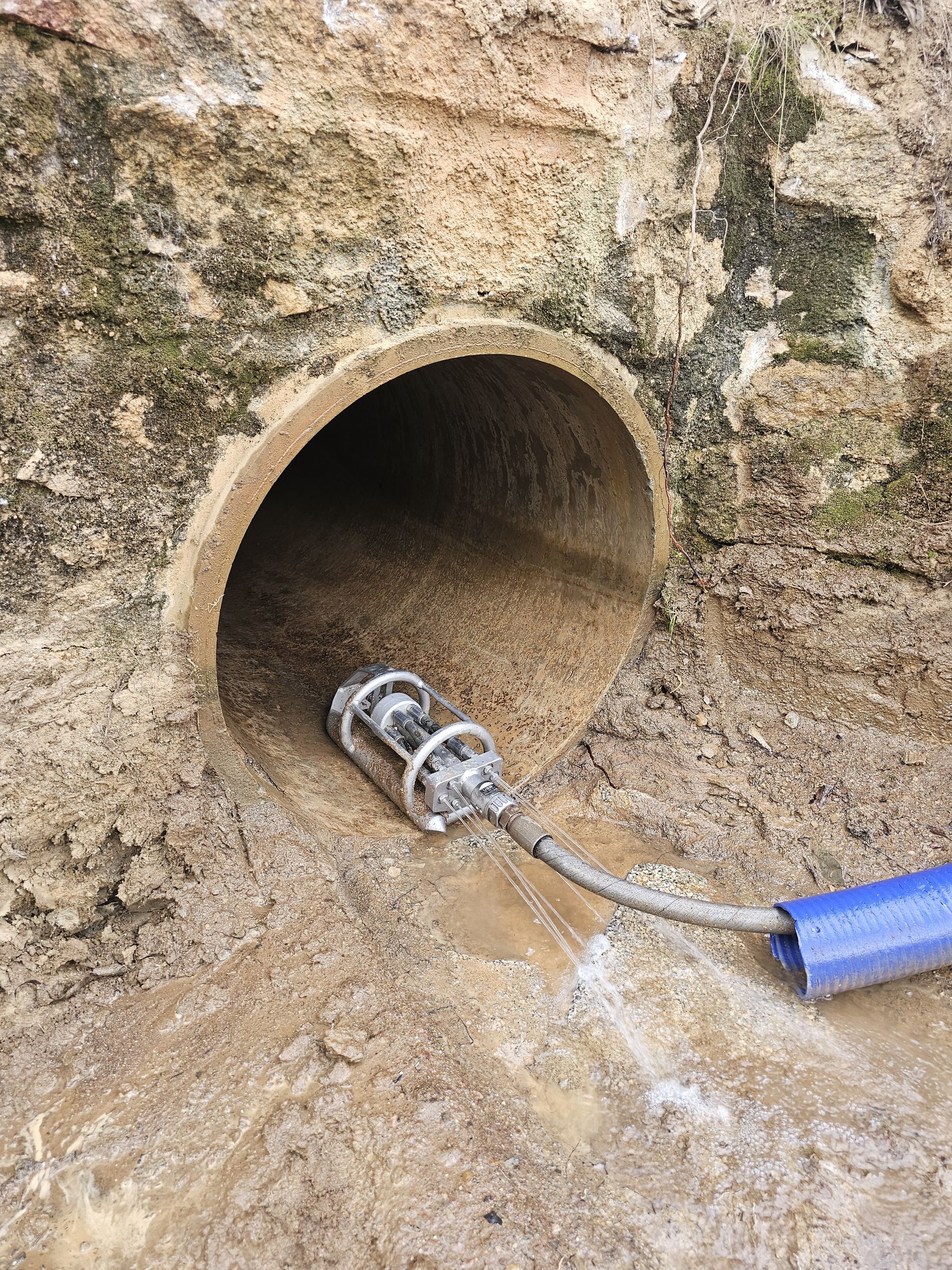 A camera probe inserted into a cylindrical opening in a rock wall, likely inspecting a pipe or drainage system — Pro Pipe Solutions in Queanbeyan, NSW