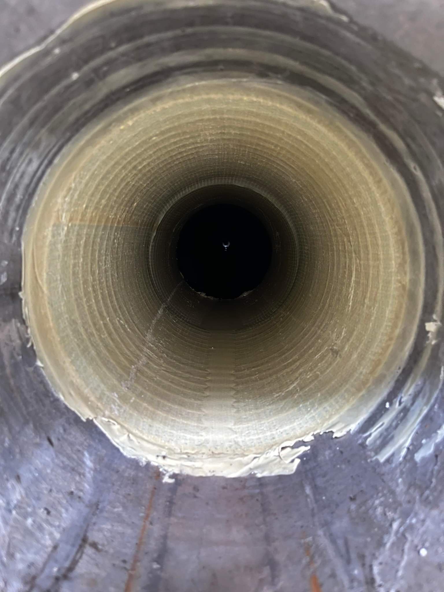 Looking down into a deep, dark, cylindrical well; rough textured walls are visible.