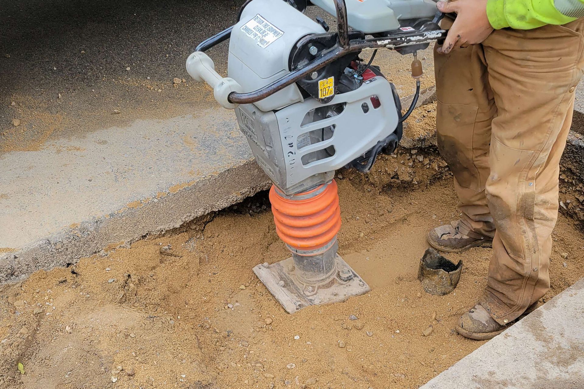Worker Compacting Soil Using Compactor