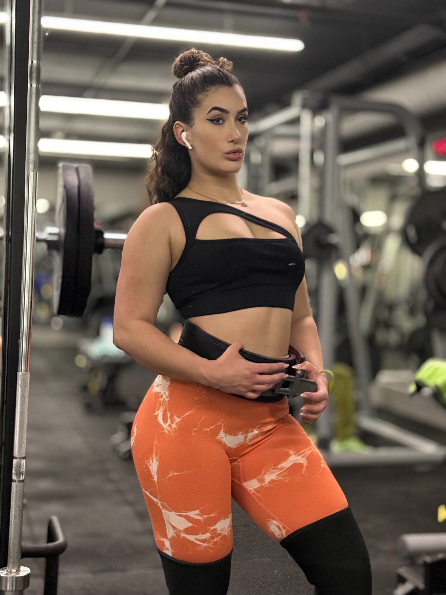 A woman is standing in front of a barbell in a gym. Anais Velvet Fitnes 