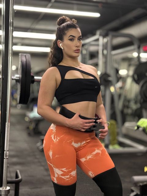 A woman is standing in front of a barbell in a gym. Anais Velvet Fitnes
