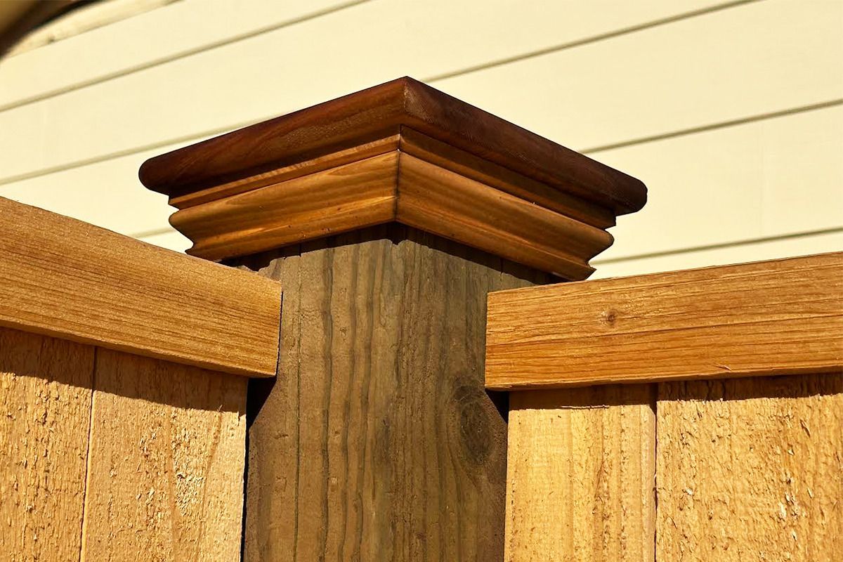 A close up of a wooden fence post with a white house in the background