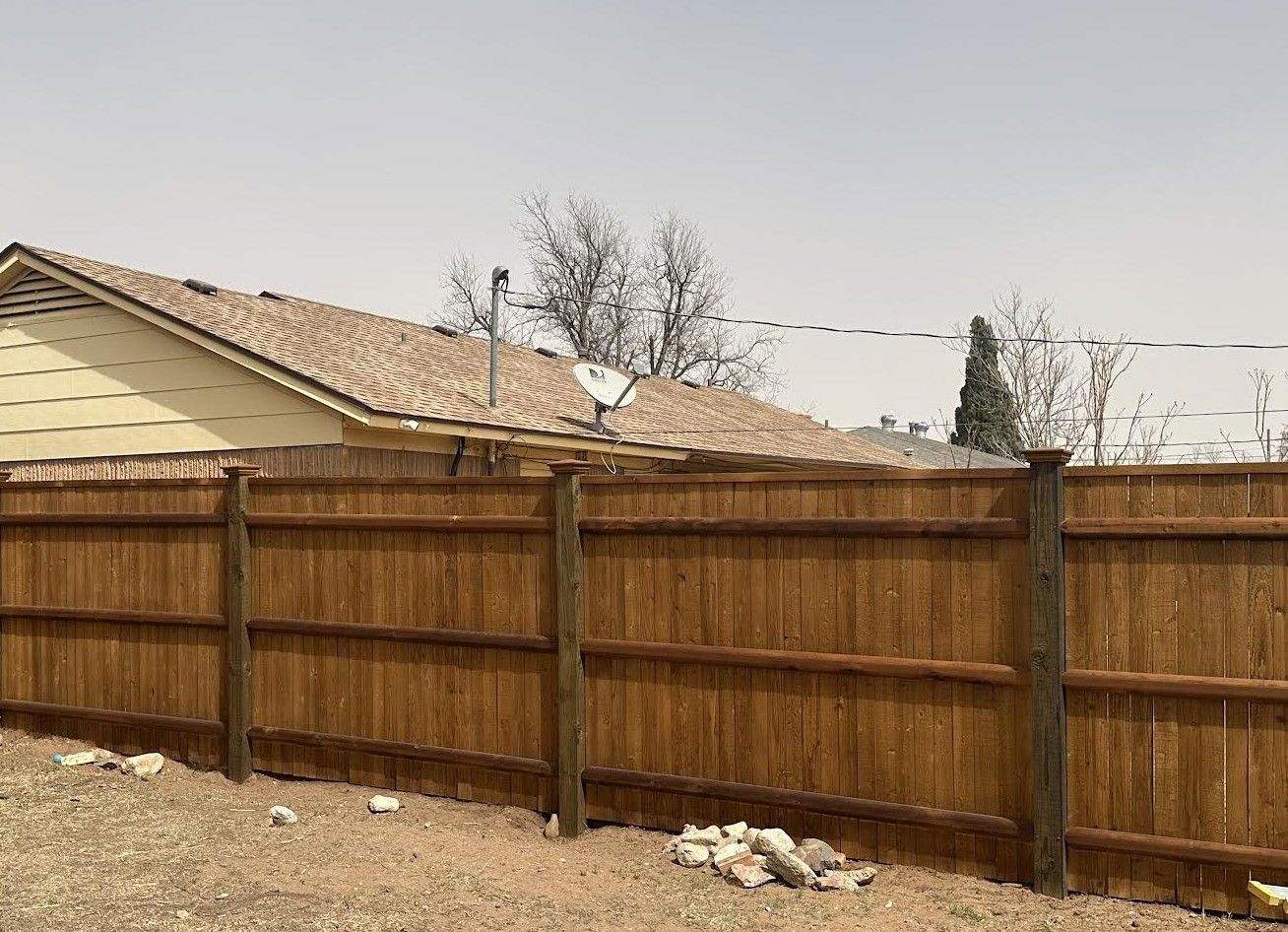 A wooden fence is in the backyard of a house.