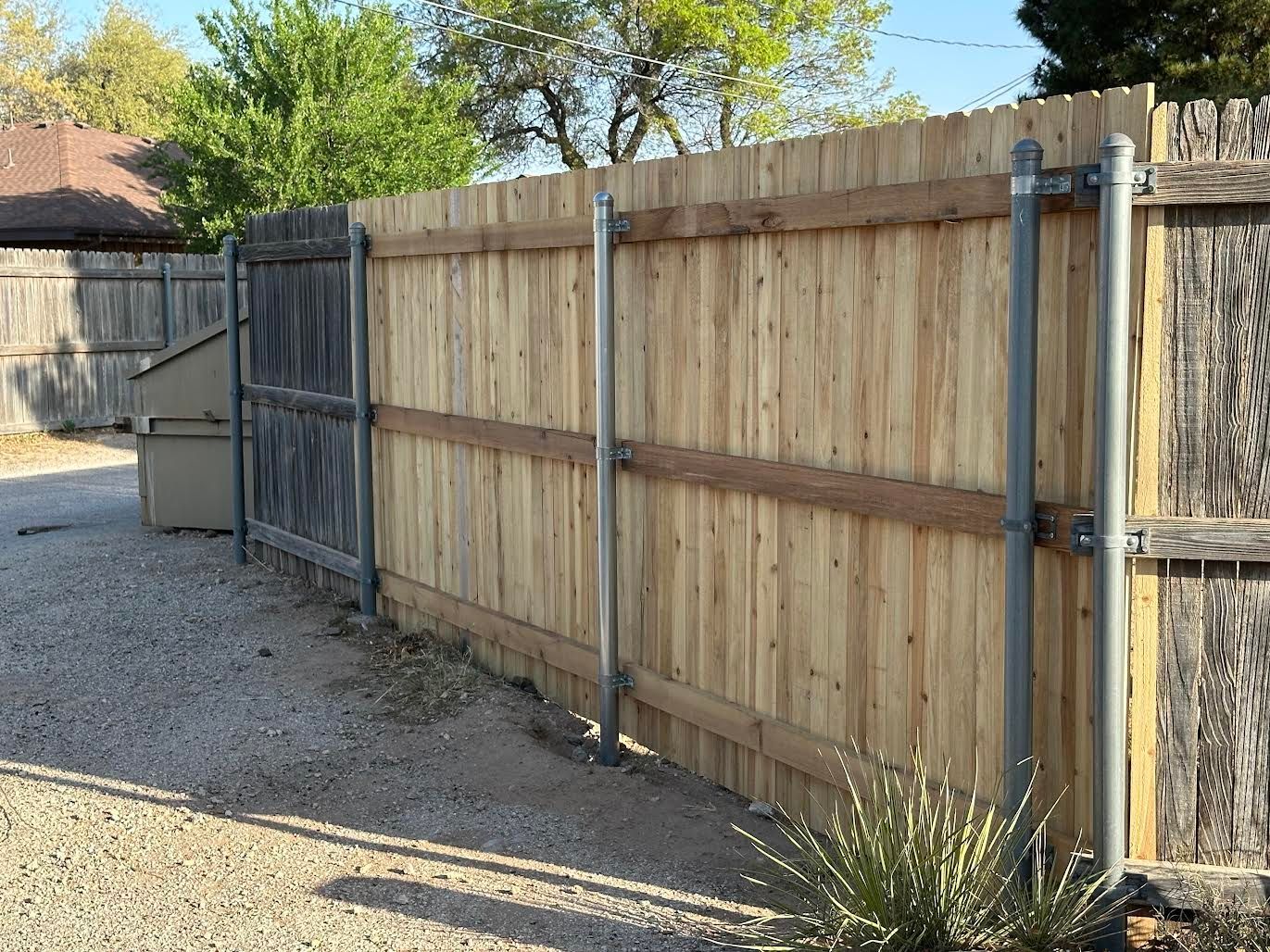 A wooden fence with metal pipes attached to it