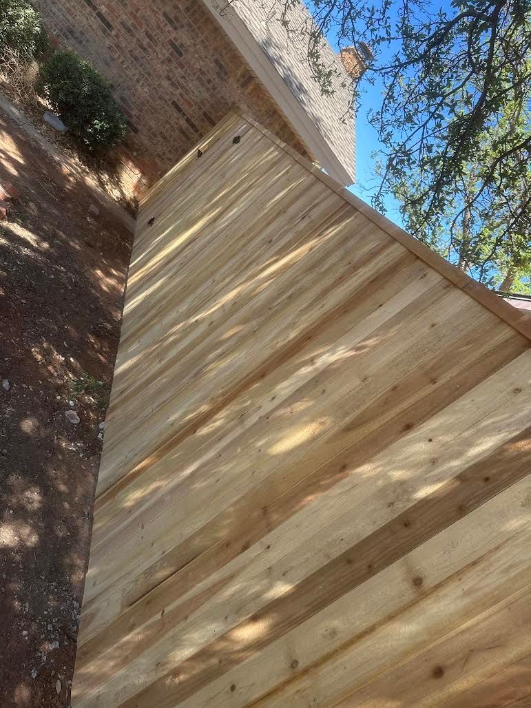 A wooden fence is sitting next to a brick wall.