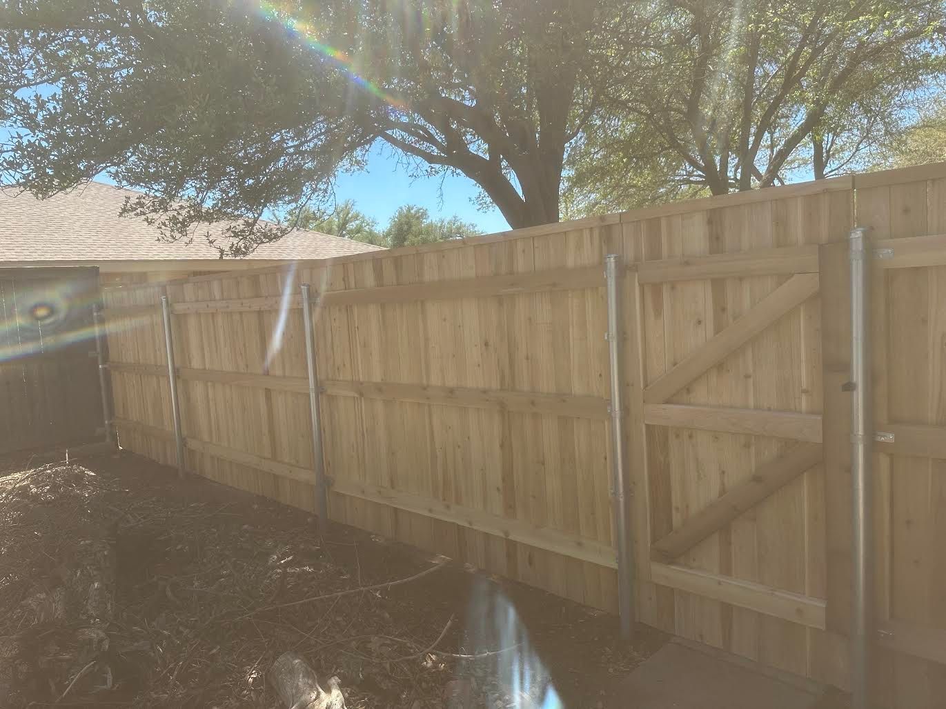 A wooden fence with a gate in the backyard of a house.