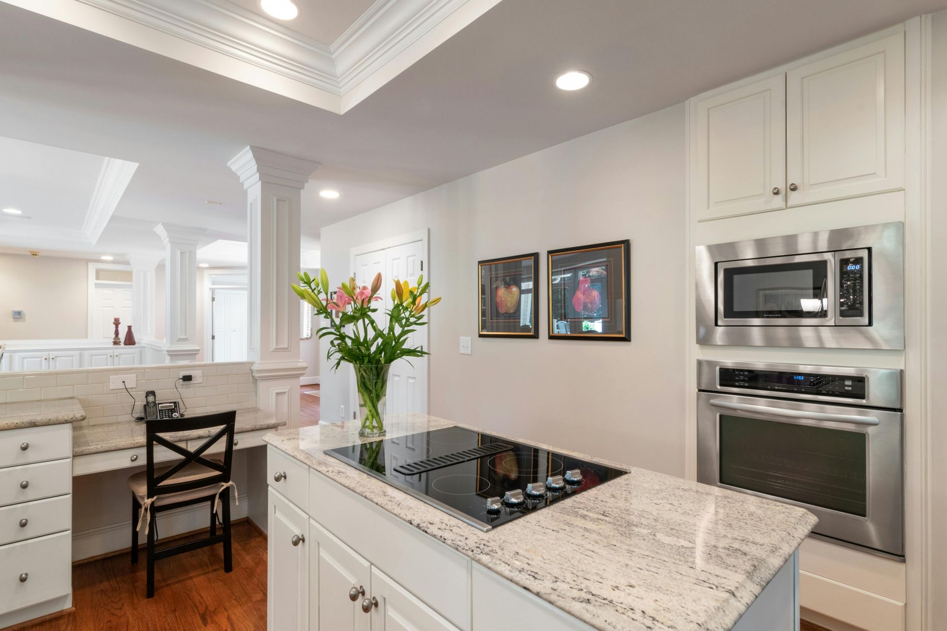 Bright modern kitchen with white cabinets, granite island, and a vase of flowers