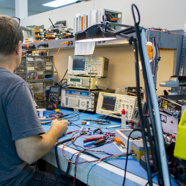 A man is sitting at a desk working on electronics