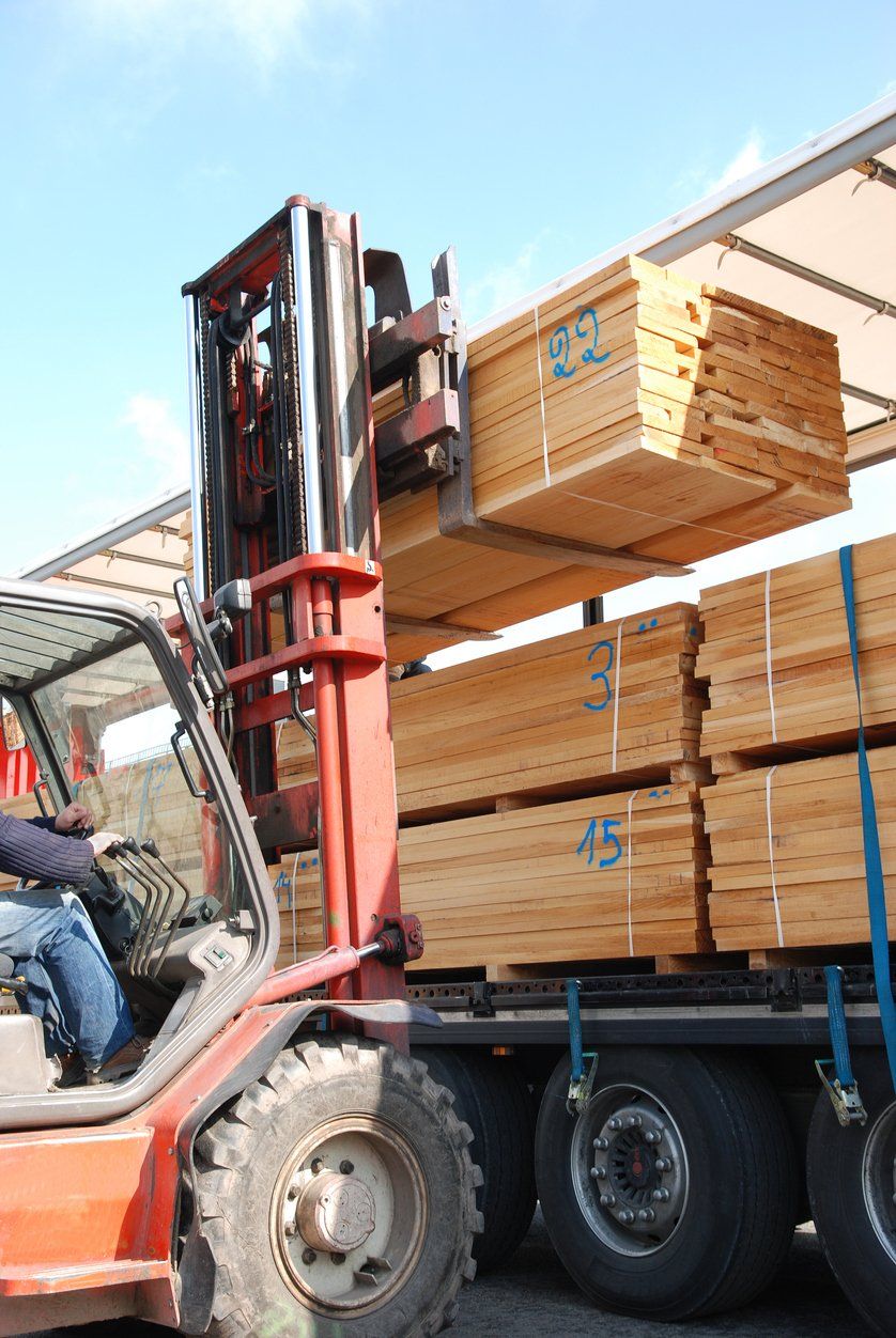 forklift is loading the truck with stacks of boards