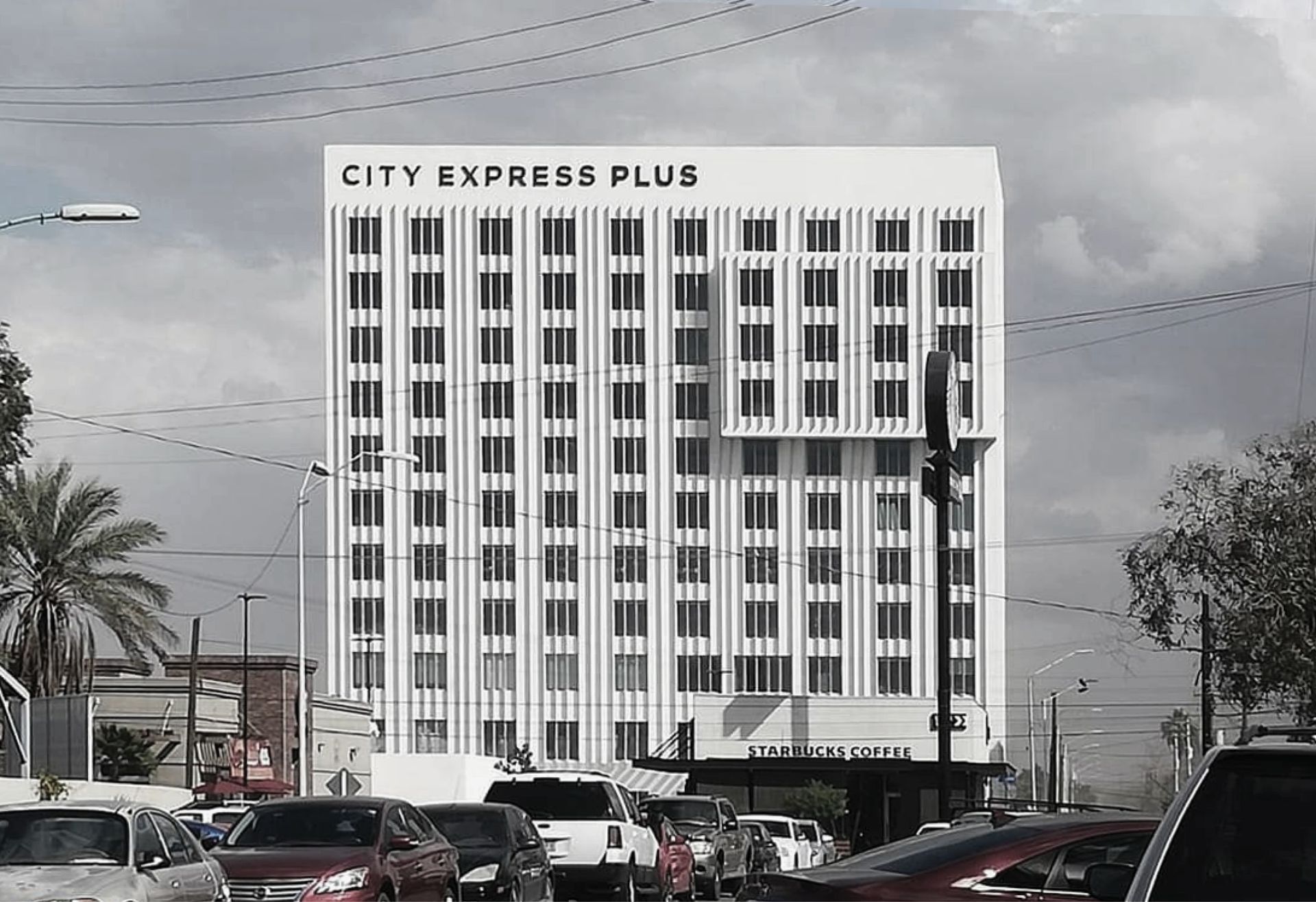 Edificio del hotel City Express Plus con coches en la carretera en primer plano.