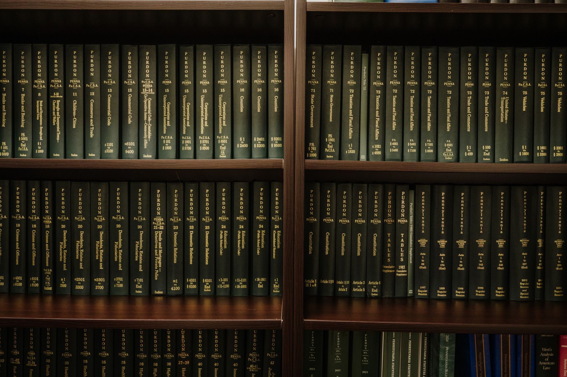 Wooden bookshelves filled with rows of black, hardcover law books with gold embossed lettering on their spines.