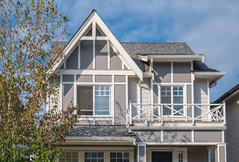 A large house with a balcony and a blue sky in the background.