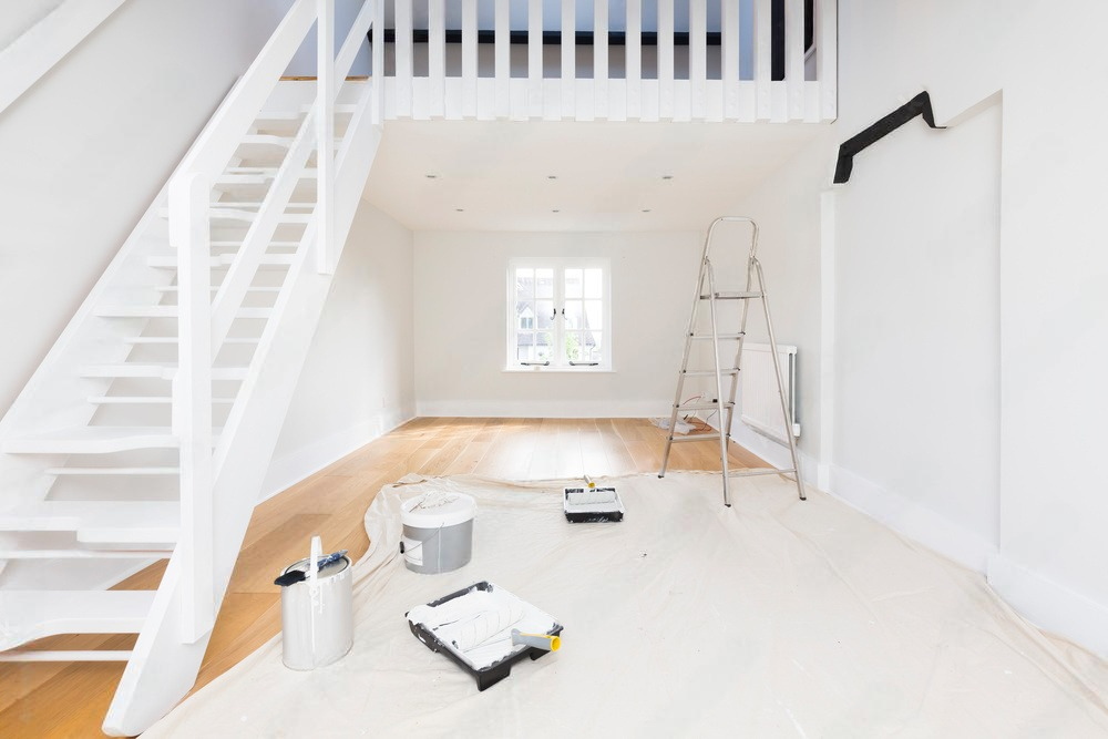 A room with stairs and a ladder in it is being painted.