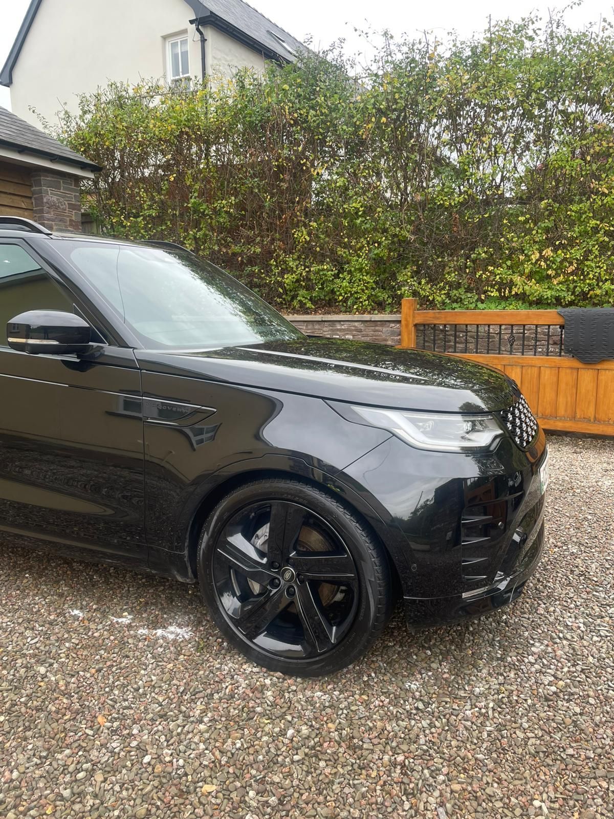Black Land Rover Discovery SUV parked on gravel driveway.