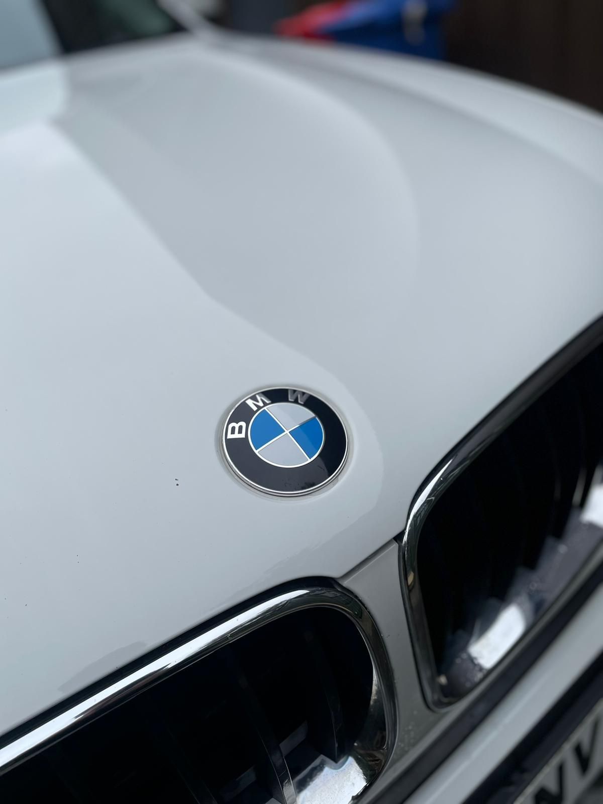 White BMW car hood with the blue and white emblem in the center.
