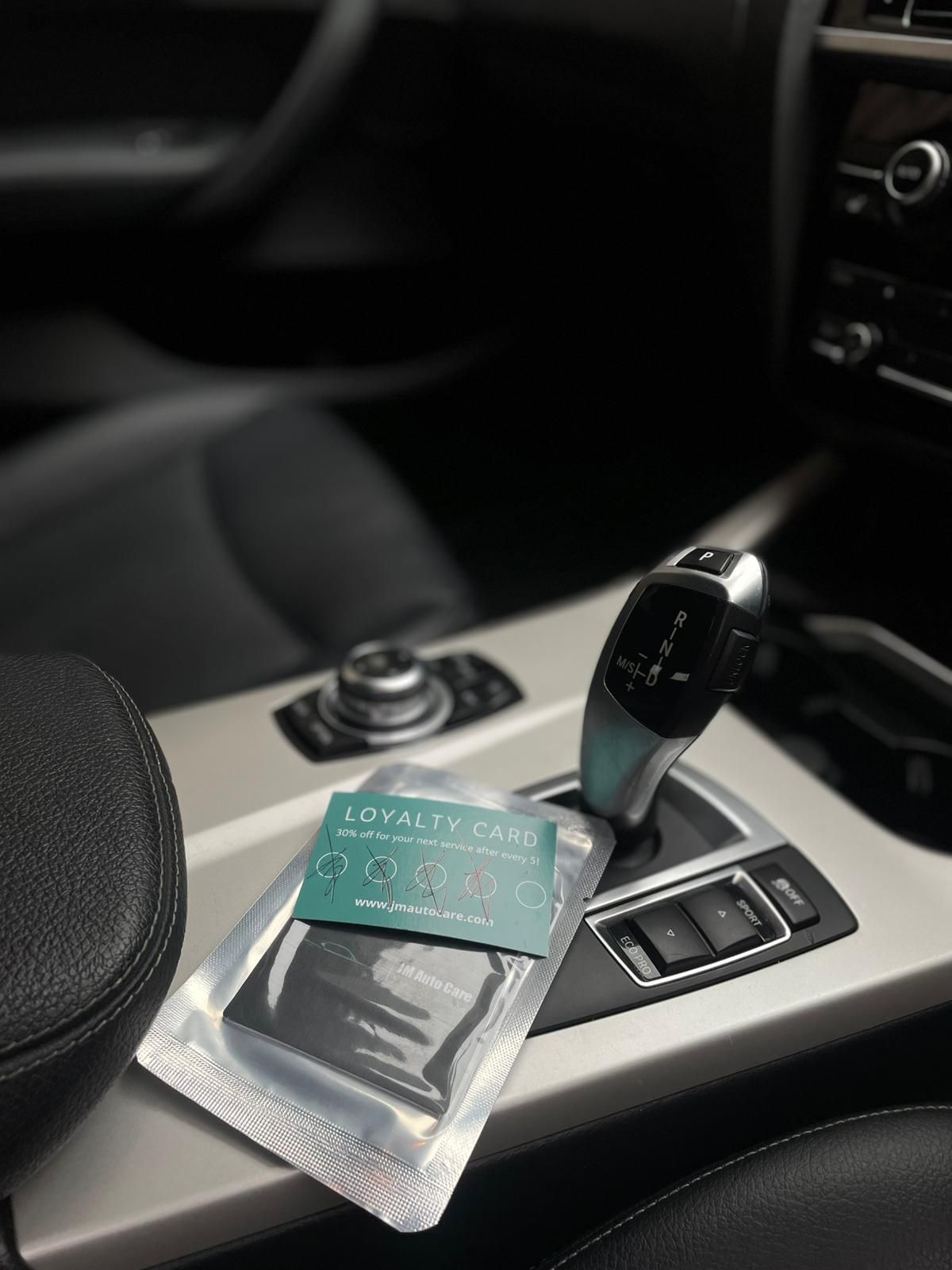 A loyalty card and packaged item rest on the console of a car near the gear shift.