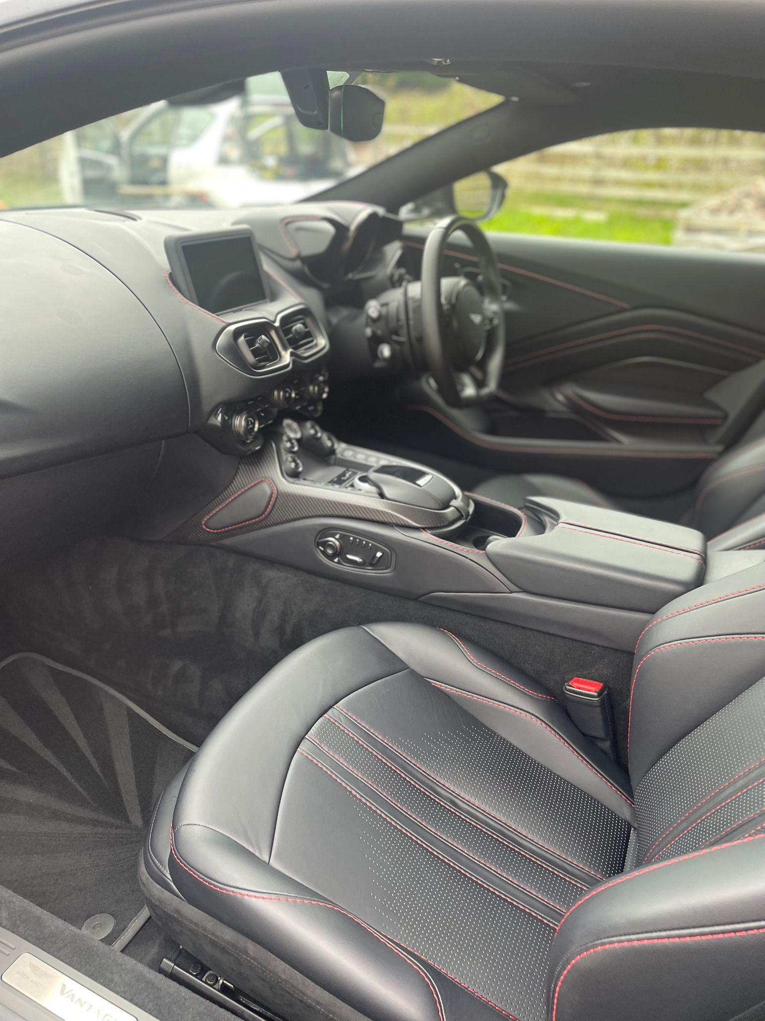 Black Aston Martin interior with red stitching accents.