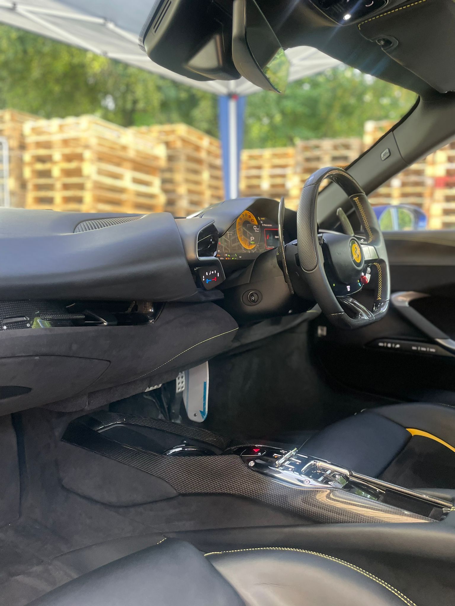 Black car interior with carbon fiber trim, yellow accents, steering wheel, and dashboard.