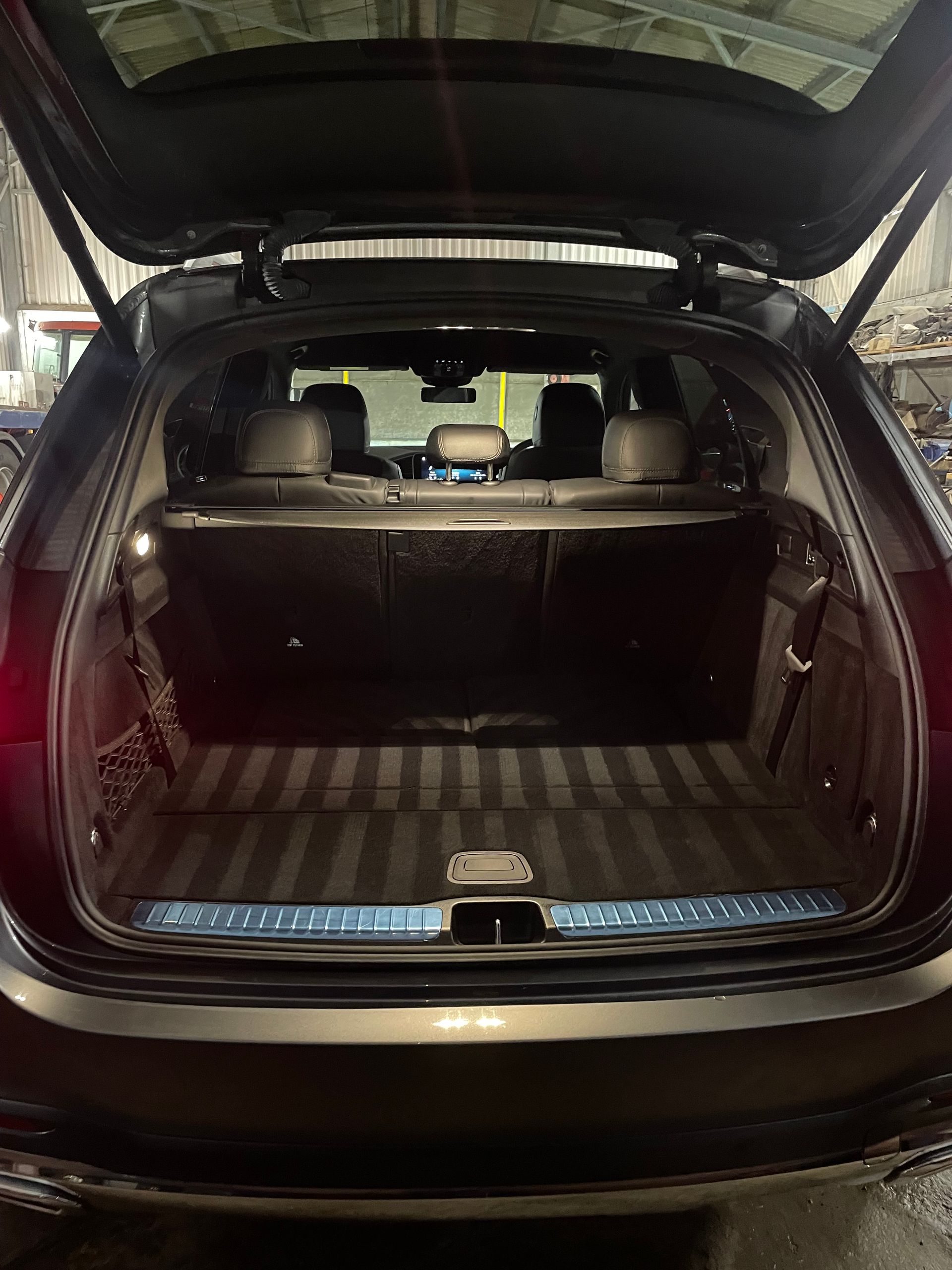 Open trunk of a dark grey luxury SUV, revealing the empty boot with detailed design and rear seats.