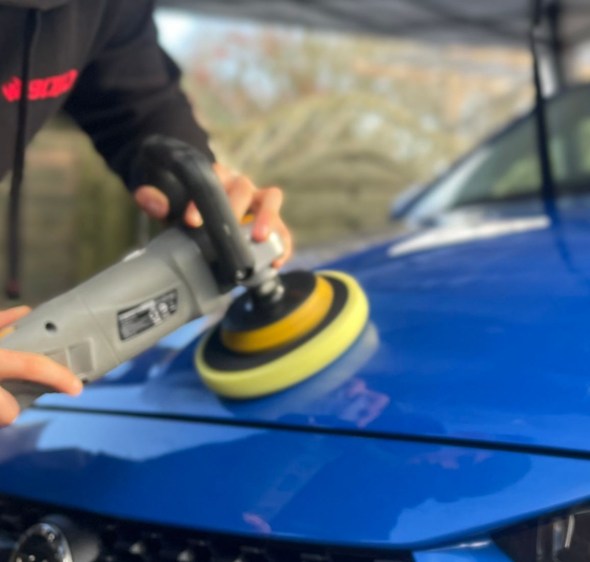 Machine polishing a blue car bonnet