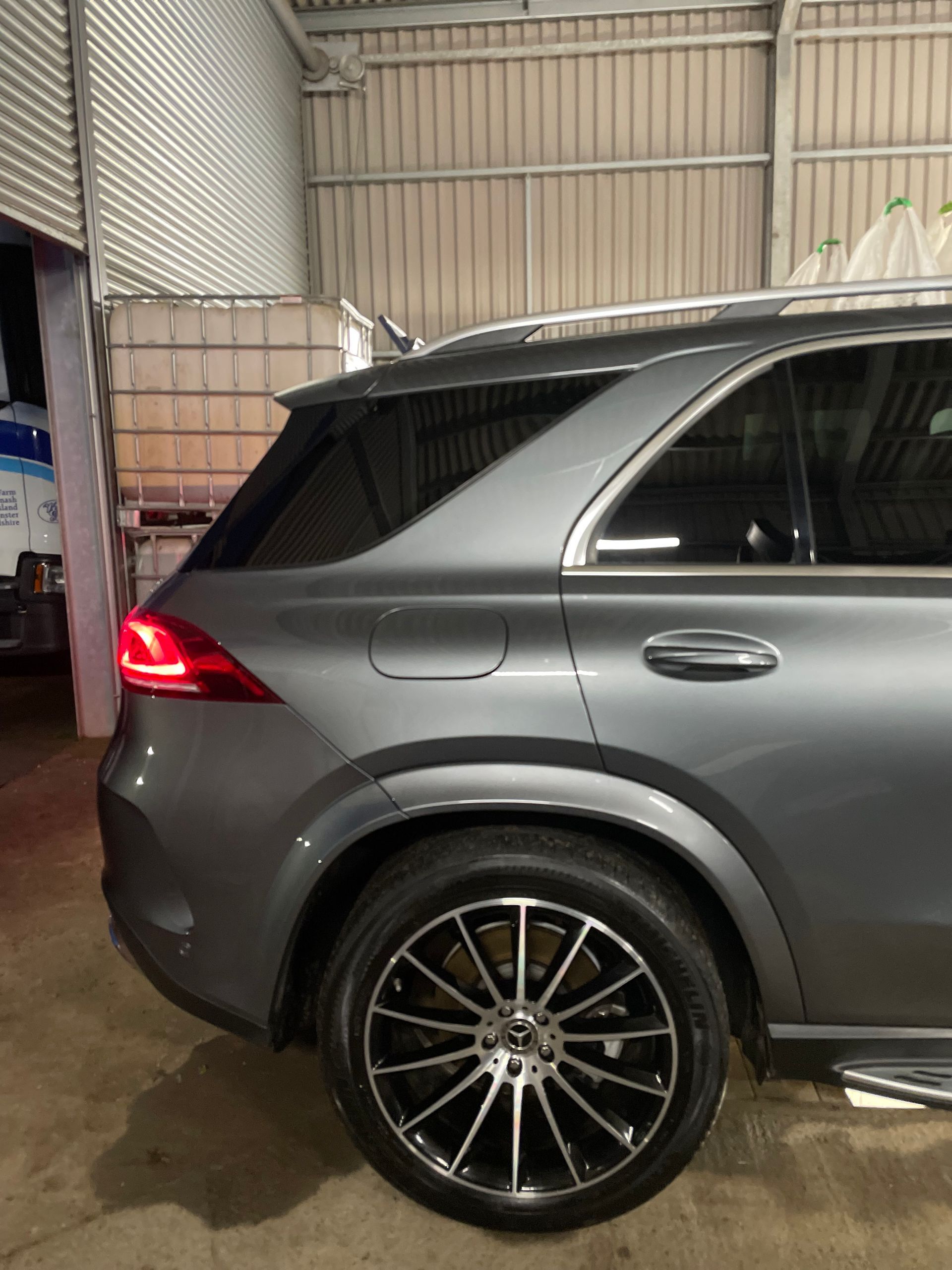 Gray Mercedes-Benz SUV, side view, black rims, parked indoors.