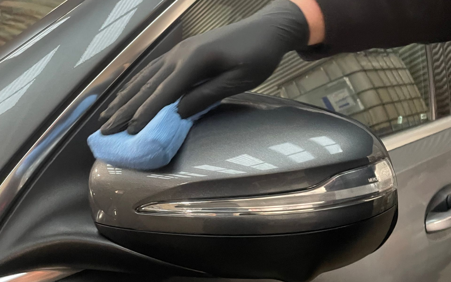 hand with black glove holding blue applicator pad applying ceramic coating