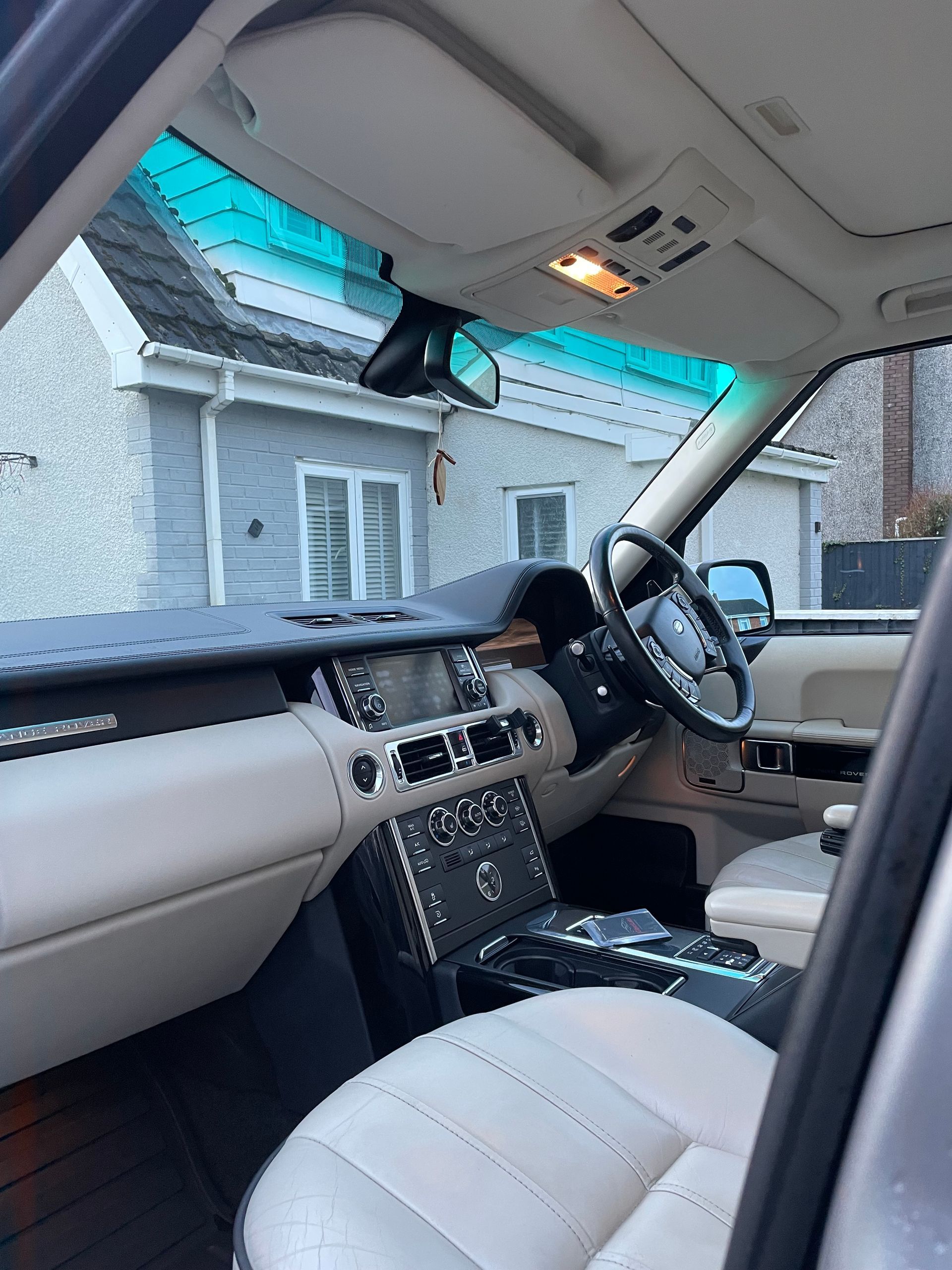 Interior view of a beige and black Range Rover, dashboard, seats, and steering wheel visible.