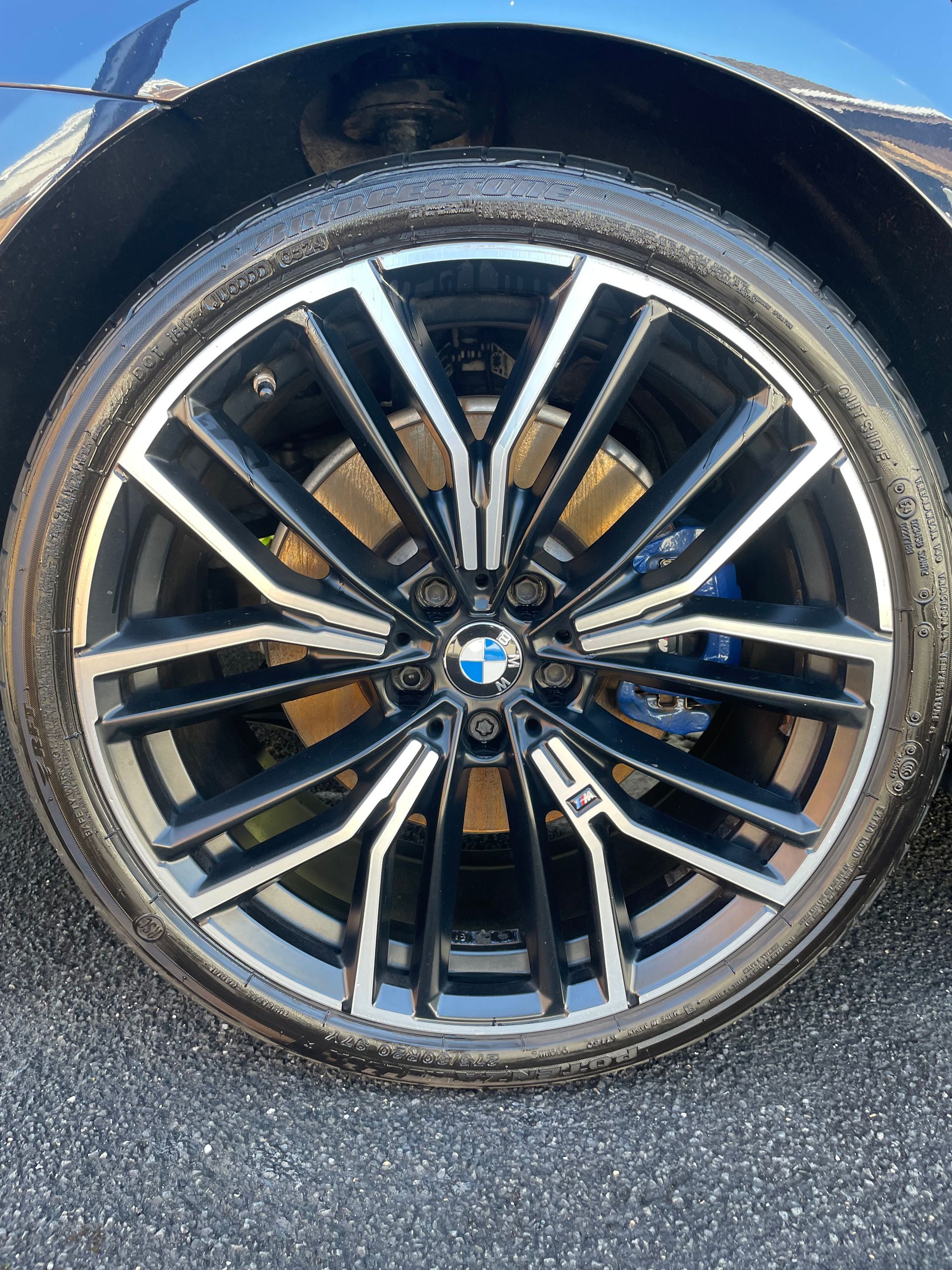 Black and silver BMW car wheel with blue brake calipers.