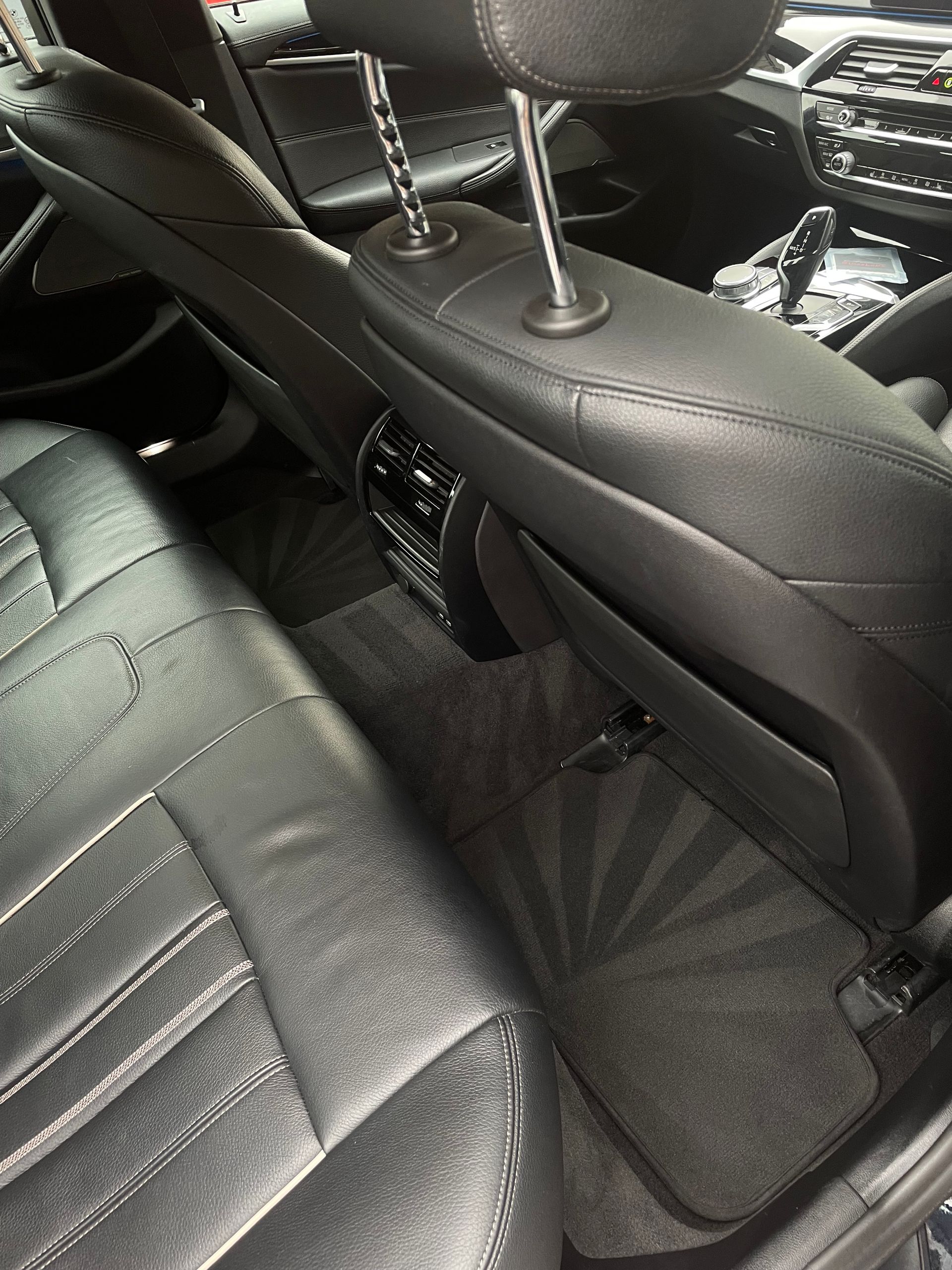Black car interior with leather seats, headrest, and floor mat.