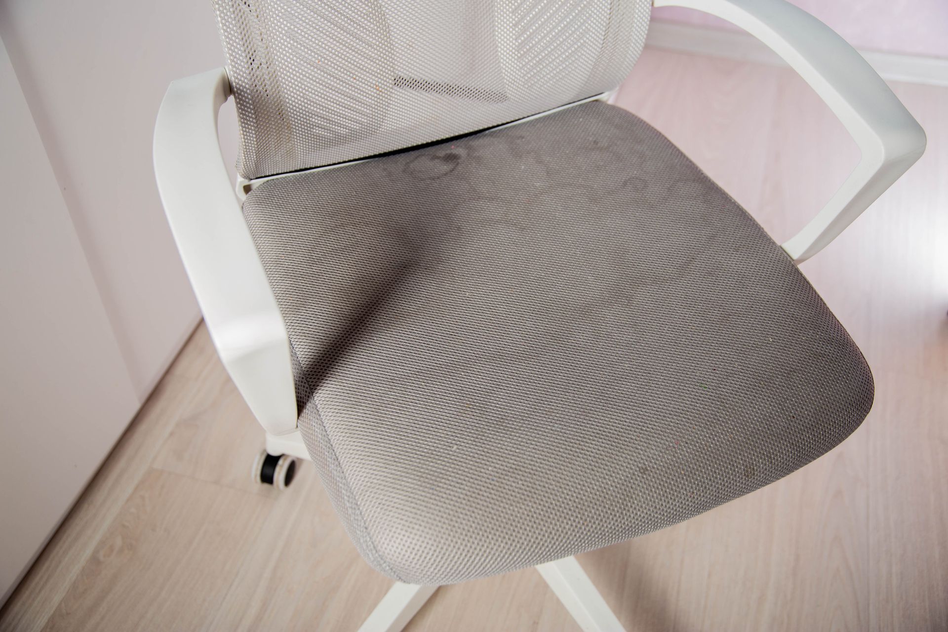 A round wooden dining table surrounded by blue and light pink velvet chairs in a modern, plant-filled living space.