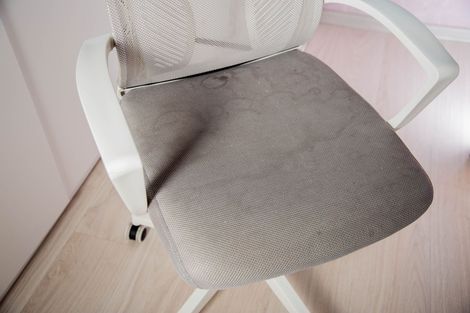 A modern lounge area with modular grey couches and yellow cushions, featuring a staircase and white tiled floor.