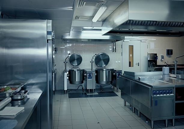 A clean, commercial kitchen with stainless steel equipment, including two large tilting kettles and prep tables.
